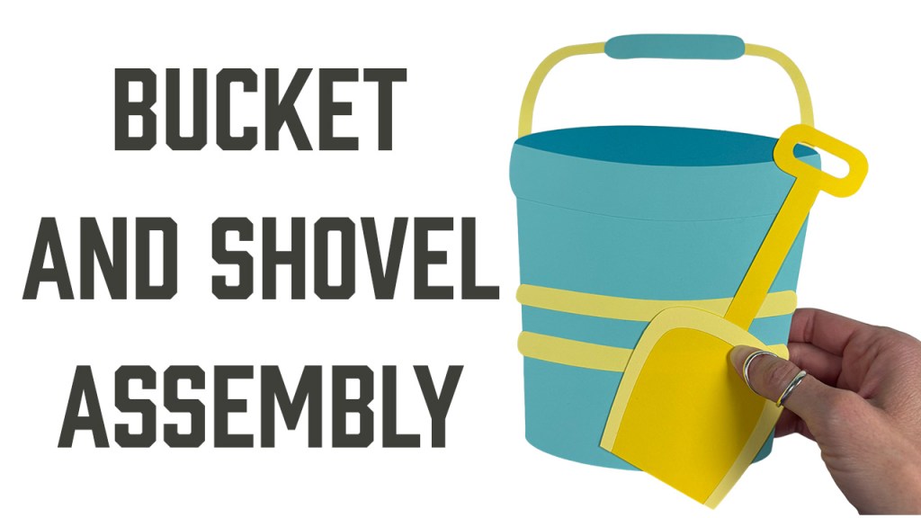 Reads "Bucket and Shovel Assembly" with a photo of a blue bucket with yellow stripes and yellow shovel made of card stock.